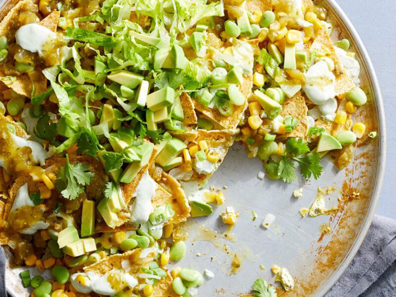 Vegan nachos verdes sprinkled wth cilantro on a gray background