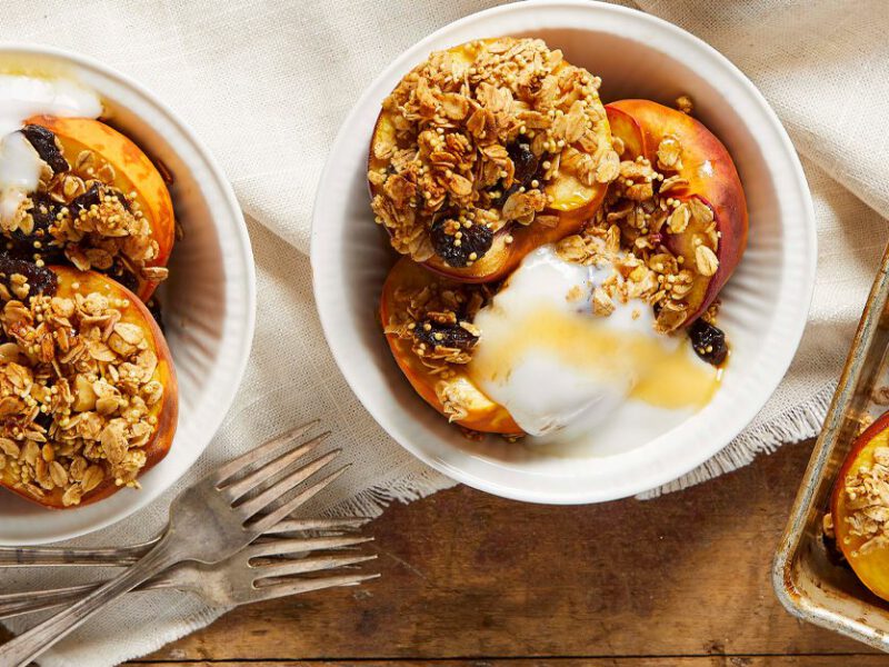 Baked Peaches with Granola Topping in white bowls on a wooden table
