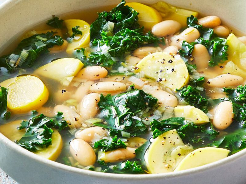 Summer Squash Soup with White Beans and Kale in a white bowl