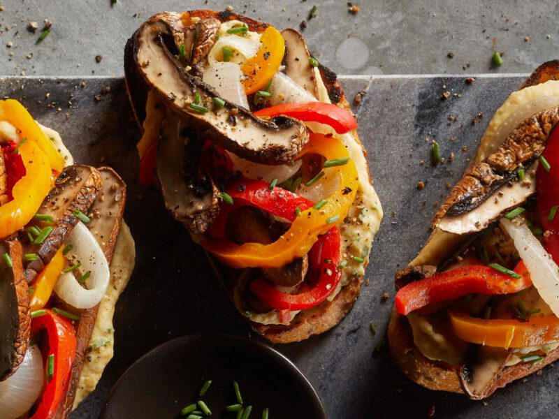 Shredded Portobello Mushroom Sandwiches with peppers and onions on a gray slate serving board