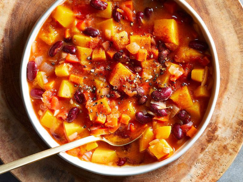 Butternut Squash and Red Bean Stew in a white bowl on a wooden serving plate