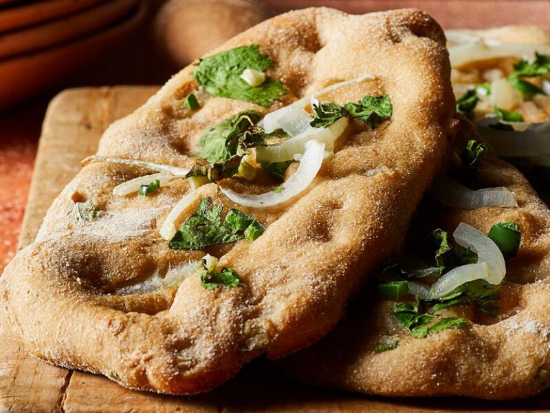 Garlic-Jalapeño Naan with fresh cilantro on a wooden cutting board