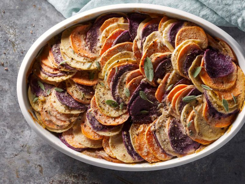 Vegan Sweet Potato Gratin with fresh sage leaves in a white casserole dish