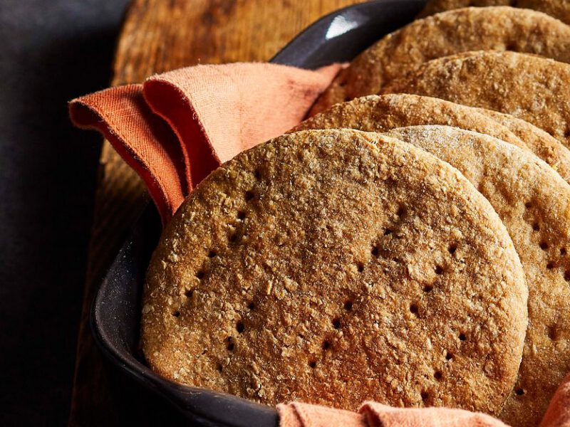 Whole Wheat Sandwich Thins stacked in a line on a peach colored dishcloth inside a serving tray