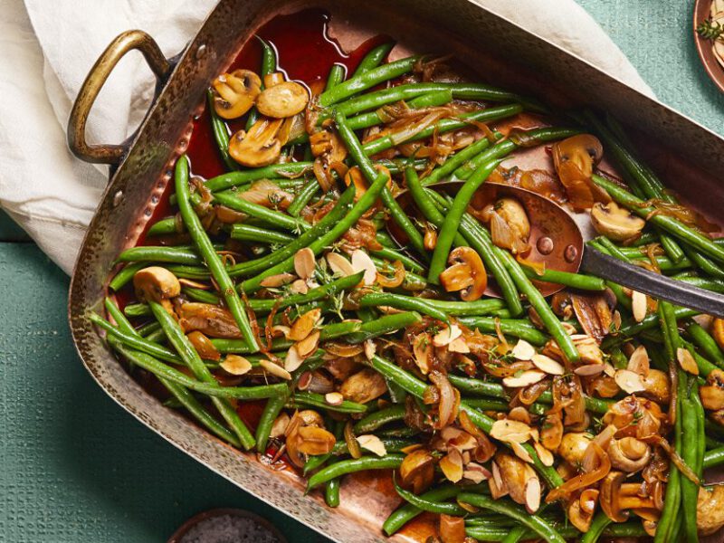 Skillet Green Beans with Caramelized Onions and Mushrooms in a serving tray on a blue table