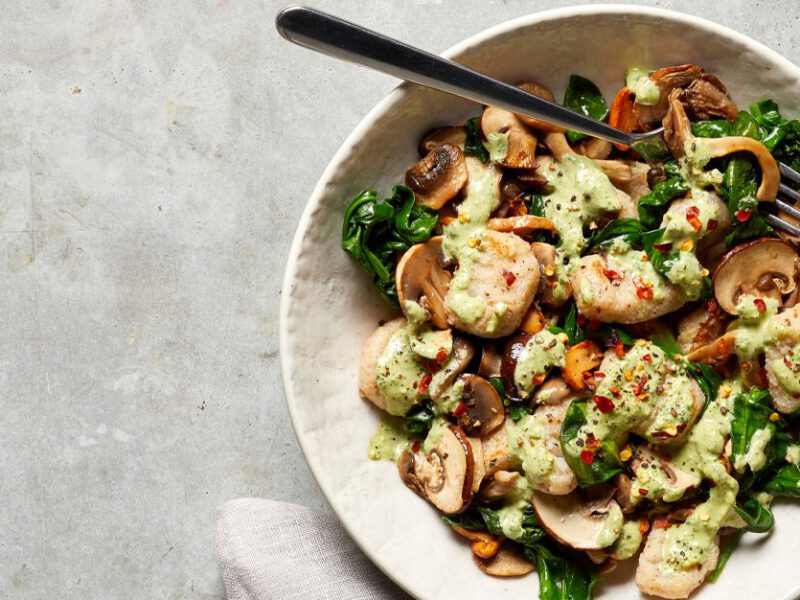 Potato Gnocchi with Mushrooms and Greens in a white bowl with a metal fork