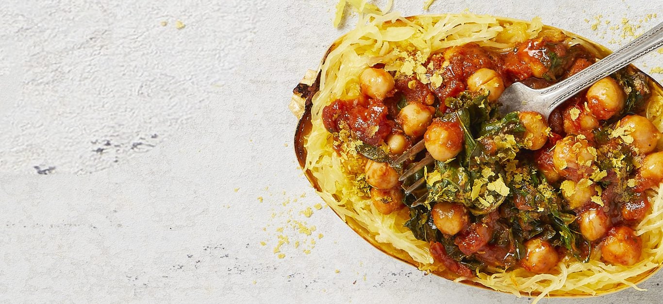 Kale Arrabbiata-Stuffed Spaghetti Squash with a metal fork on a white marble counter