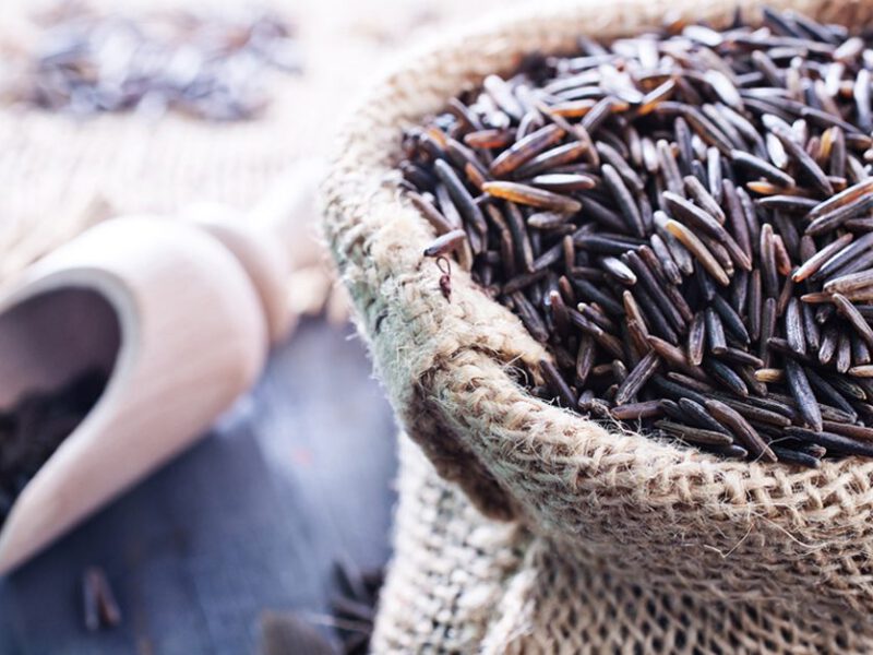 Wild rice in a bag and scoop on a wooden table
