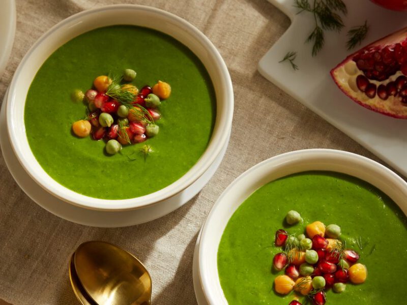 Super Greens Soup with Chickpeas in white bowls next to an open pomegranate