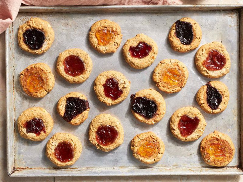 Jam Dot Holiday Cookies - Photo taken from above of a baking sheet full of finished cookies with jam dots in the center