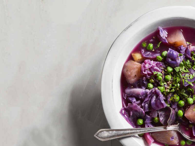 Hearty Purple Cabbage Soup in a white bowl with metal spoon