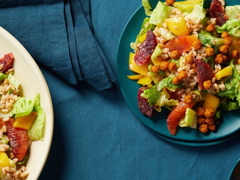 Blood Orange-Farro Salad with Crispy Chickpeas on a blue plate with a larger bowl of salad in a white dish