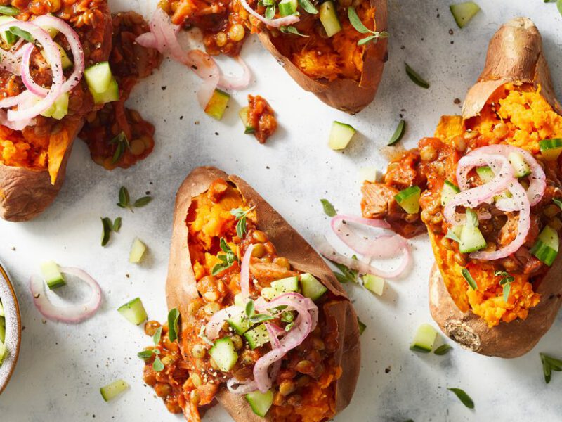 Barbecue Stuffed Sweet Potatoes with onion and cucumbers on a white countertop