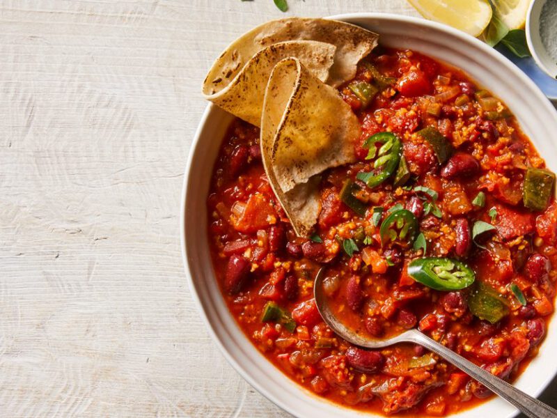 Hearty Red Bean Chili in a white bowl with tortillas on the side