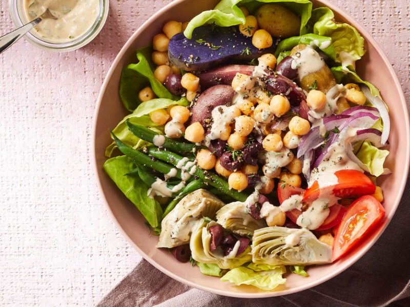 Vegan Niçoise Salad Bowls in a light pink dish with a small bowl of tahini dressing