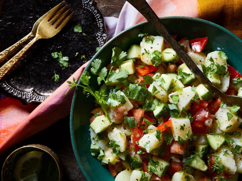 Indian-Spiced Potato Salad in a blue bowl with metal serving spoon
