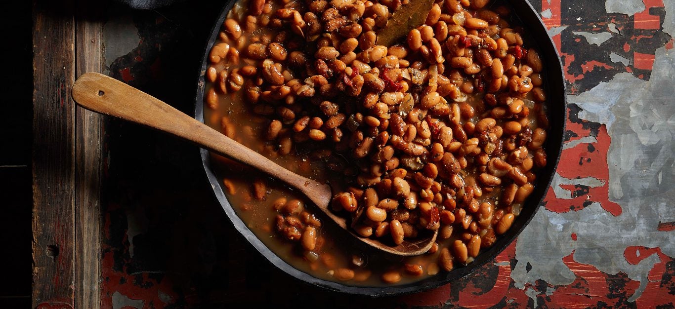 Multicooker Pot o’ Beans in a skillet with a wooden spoon