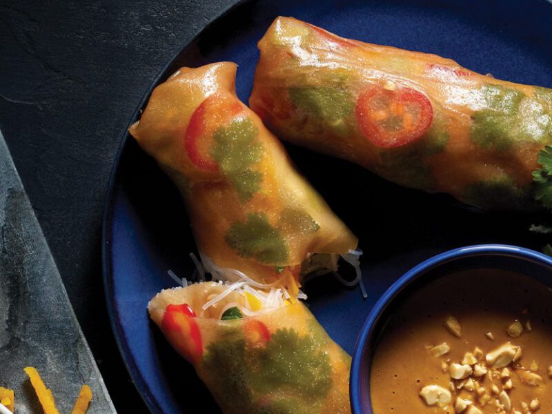 Squash and Bean Thread Noodle Spring Rolls on a blue plate with peanut sauce