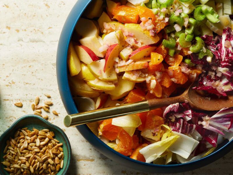 Chopped Winter Salad with Meyer Lemon Vinaigrette in a blue bowl with a serving spoon