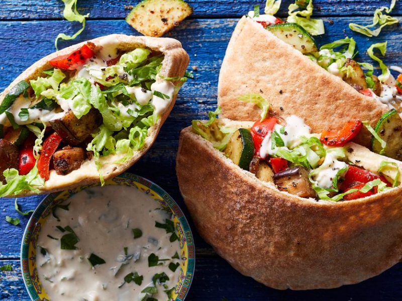 Middle Eastern Pita Pocket Sandwiches with a bowl of tahini sauce on blue wooden table