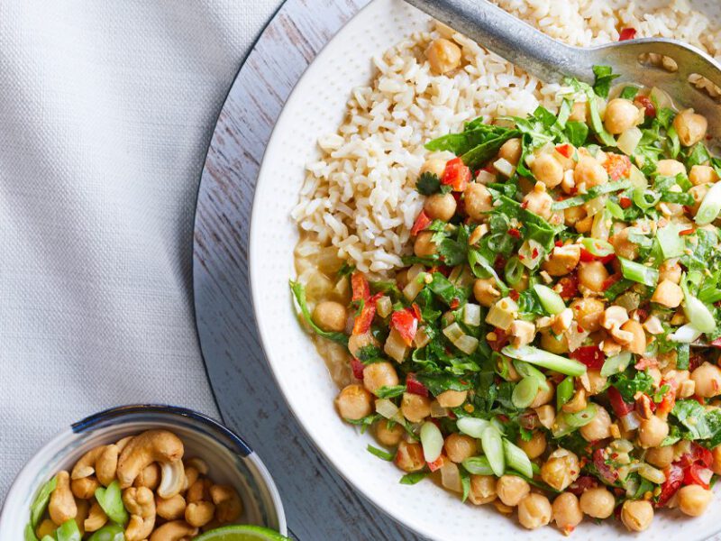 Thai Green Curry Chickpeas with Spinach in a white bowl with a metal serving spoon