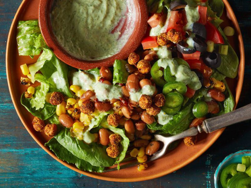Cilantro Ranch Bean Salad in an orange bowl on a wooden tabletop