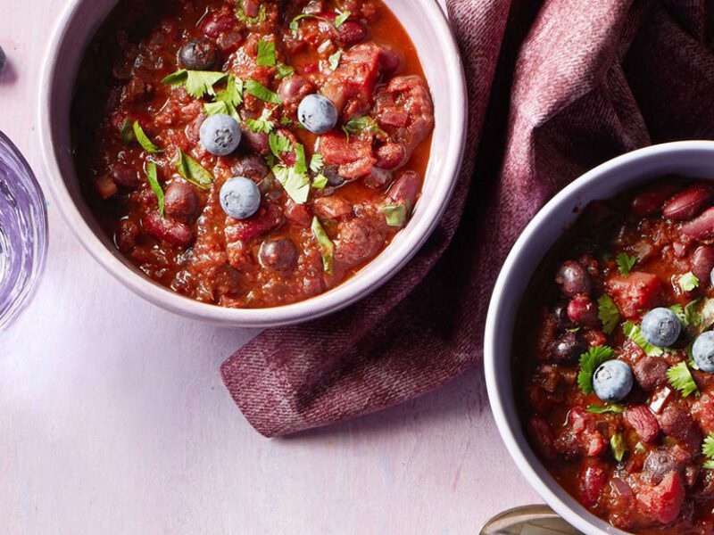 kidney bean chili blueberries in white bowls with a purple cloth napkin