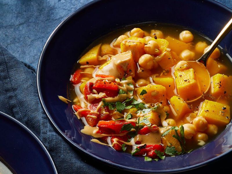 Roasted Red Pepper and Pumpkin Soup with Chickpeas in blue ceramic bowls with a metal soup spoon