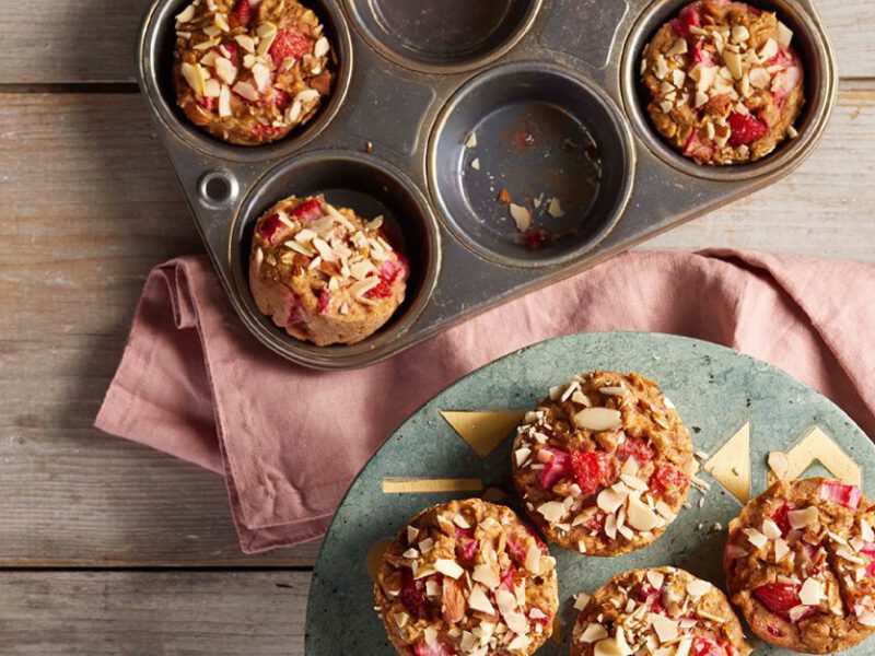 strawberry rhubarb muffins in a muffin tin and an on gray plate with a pink napkin
