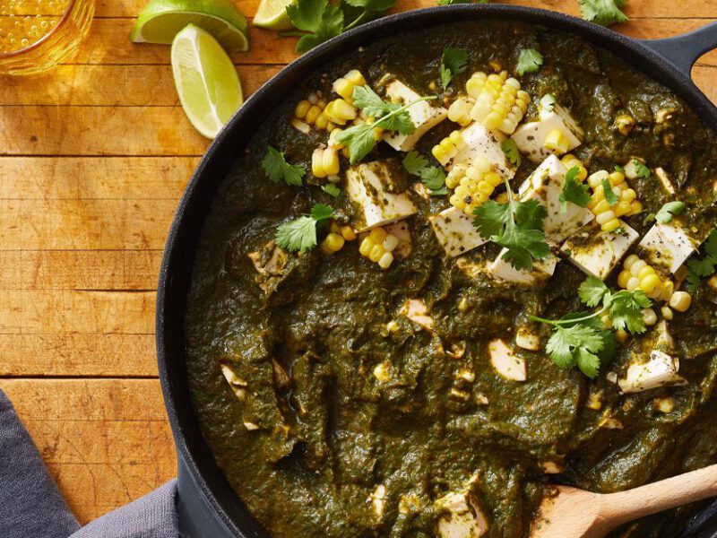 Beet Greens and Spinach Saag with Tofu in a skillet on a wood tabletop