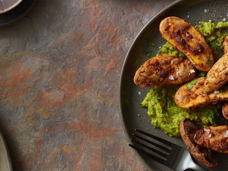 Air-Fried Fingerling Potatoes with a green sauce on a black plate