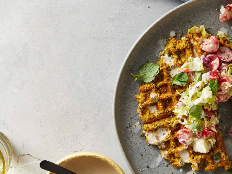 Falafel made in a waffle maker, topped with a tahini-dressed chopped salad