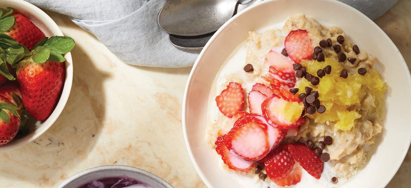 Banana Split Oatmeal Bowls in a white dish with a bowl of strawberries to the left
