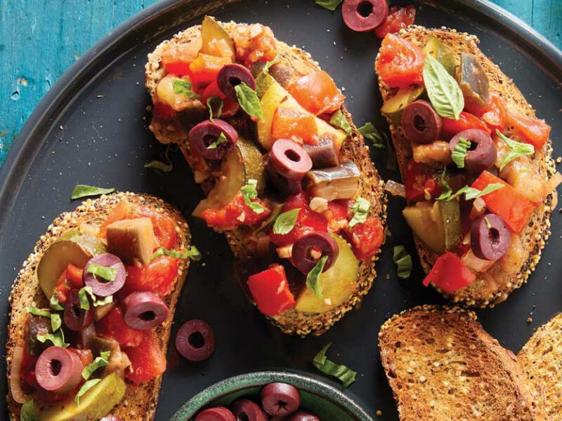 Ratatouille Bruschetta on a black plate on a turquoise tabletop