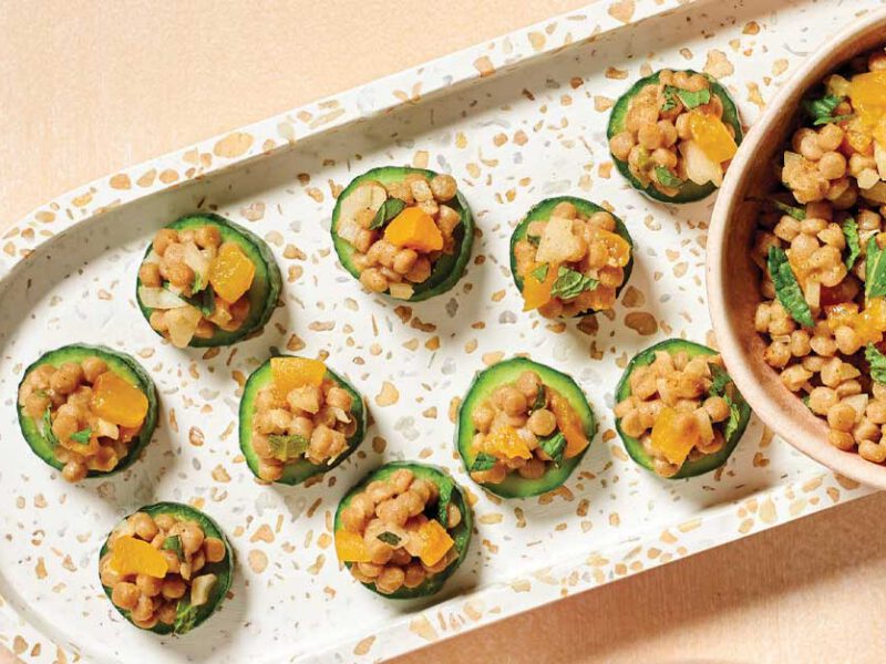 Spiced-Couscous Cucumber Bites on a white ceramic tray with a bowl of extra filling to the right