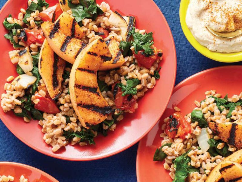 Farro Pilaf with Veggies and Blackened Melon on pink plates against a blue tabletop