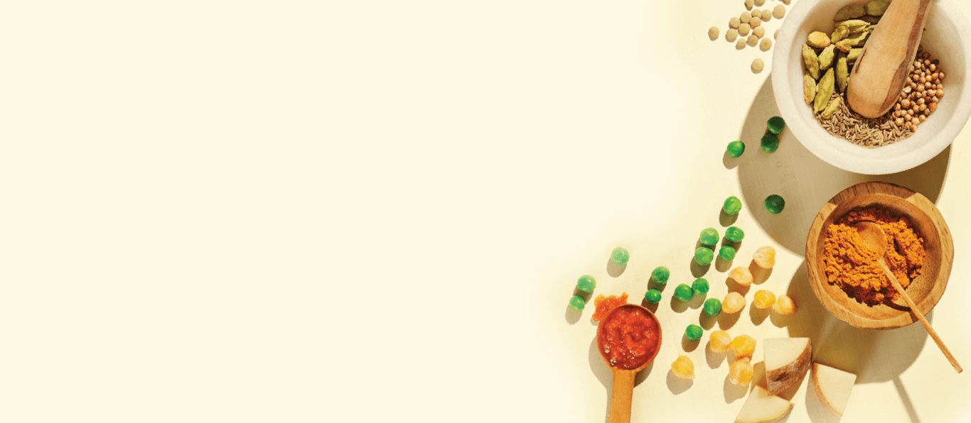 Image of ingredients on a table such as chickpeas, peas, potatoes and spices used in Forks Over Knives Frozen Bowls