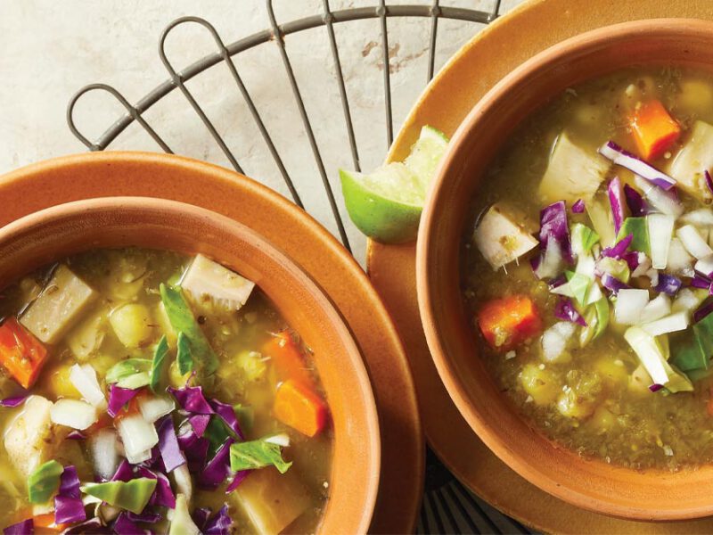 Jackfruit Pozole Verde in orange terracotta bowls with lime wedges on the side
