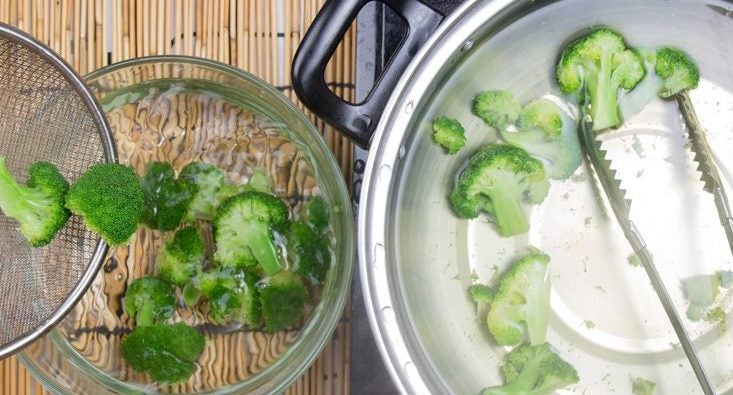 Broccoli is removed from a pot of water for blanching