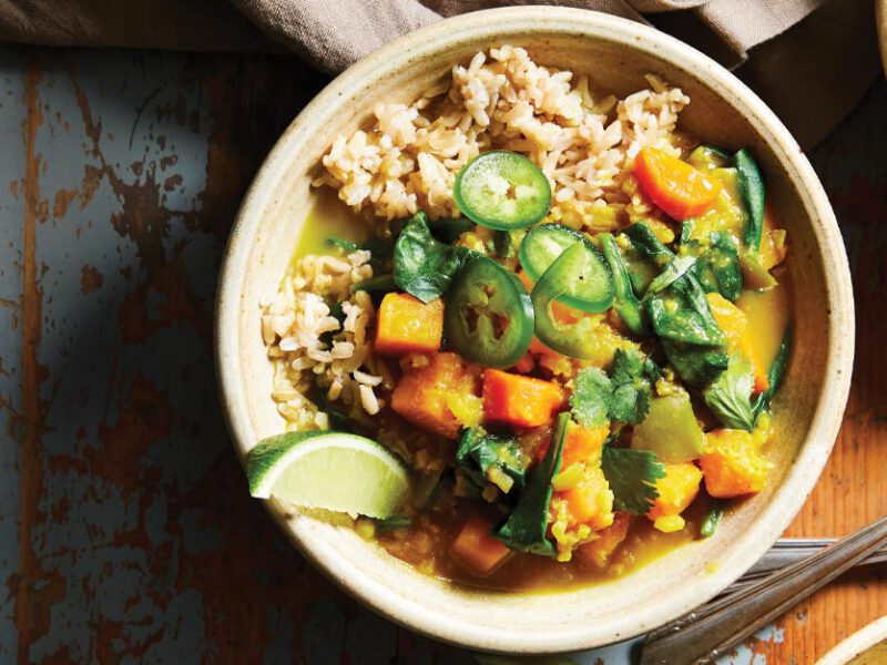 Curried Butternut Squash and Cauliflower Stew in white bowls against a brown and blue tabletop