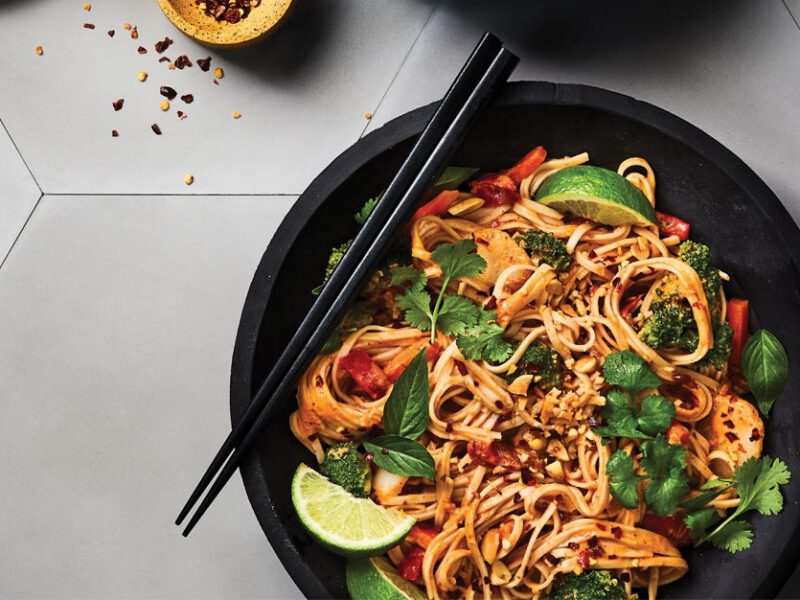 Thai Red Curry Noodles with Mixed Veggies in a black bowl with black chopsticks