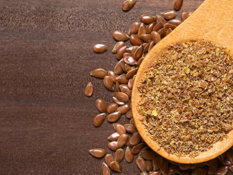 Ground and whole flaxseeds on a wooden table