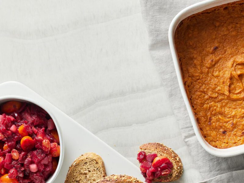 Sweet Potato Spoon Pudding in a casserole dish with a side of cranberry relish