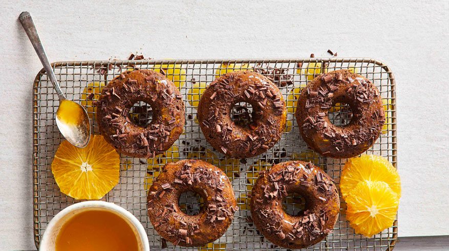 Vegan Chocolate Orange Dessert Doughnuts on a wire tray with sliced orange next to them