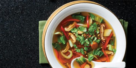 Vegan Sweet and Sour Vegetable Soup in a white bowl with a spoon beside it