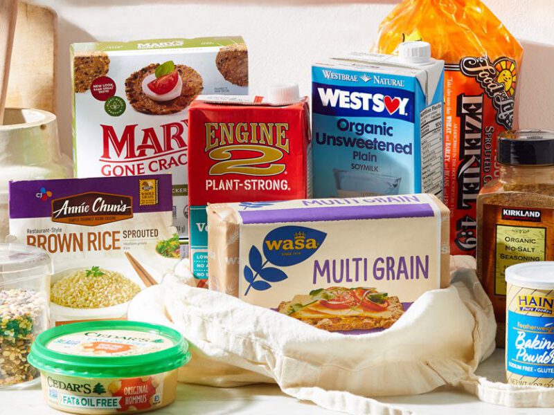 An array of oil-free vegan food products found at the grocery store, spread out on a kitchen counter, for whole-food, plant-based shoppers