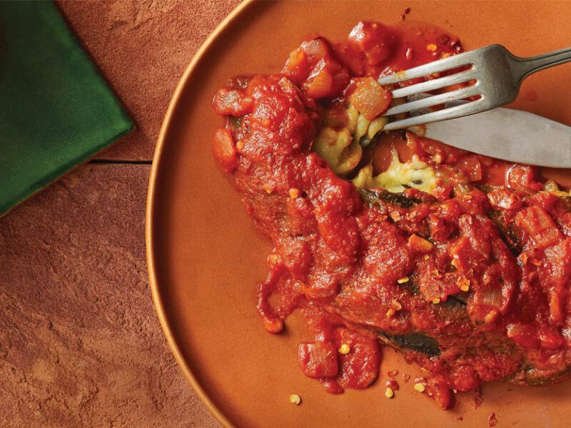 Vegan Chile Relleno on an orange plate with metal fork and knife