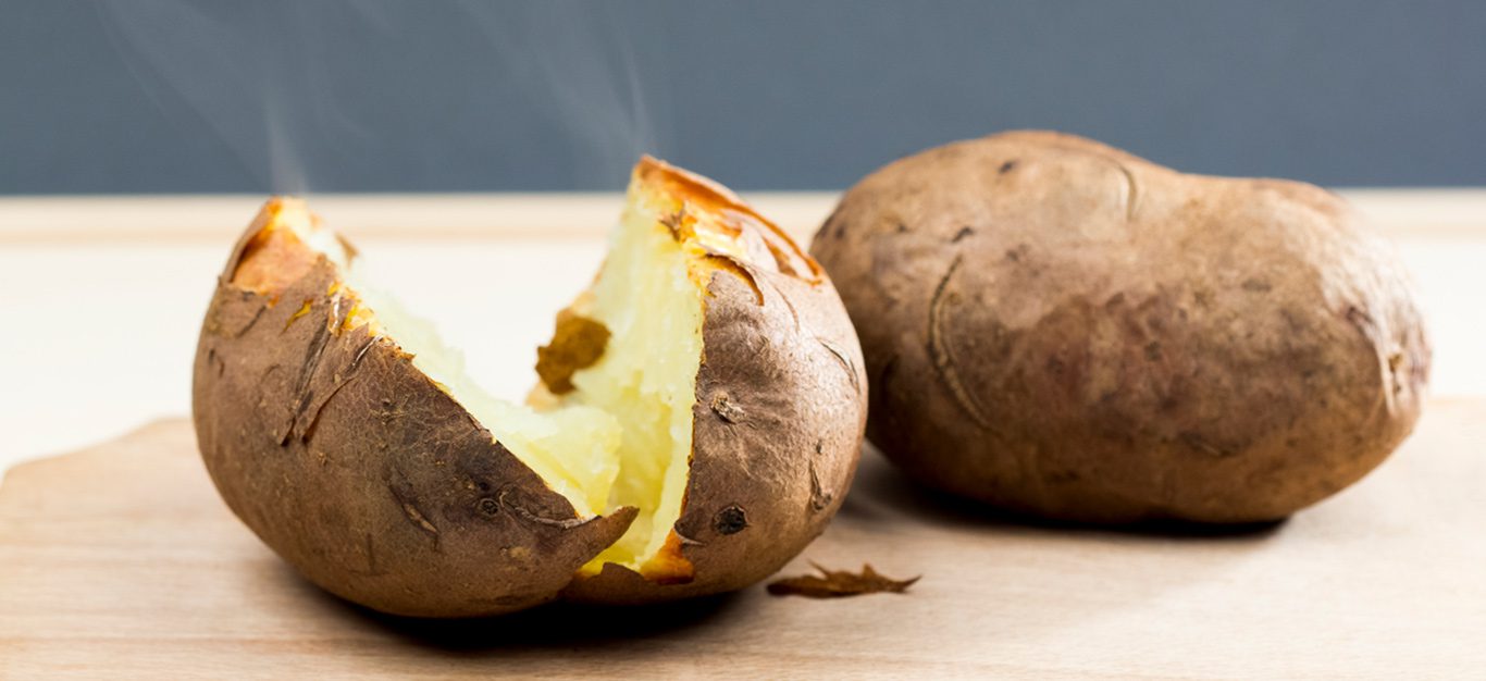 A baked potato cut in half and steaming fresh from the oven