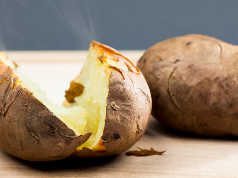 A baked potato cut in half and steaming fresh from the oven