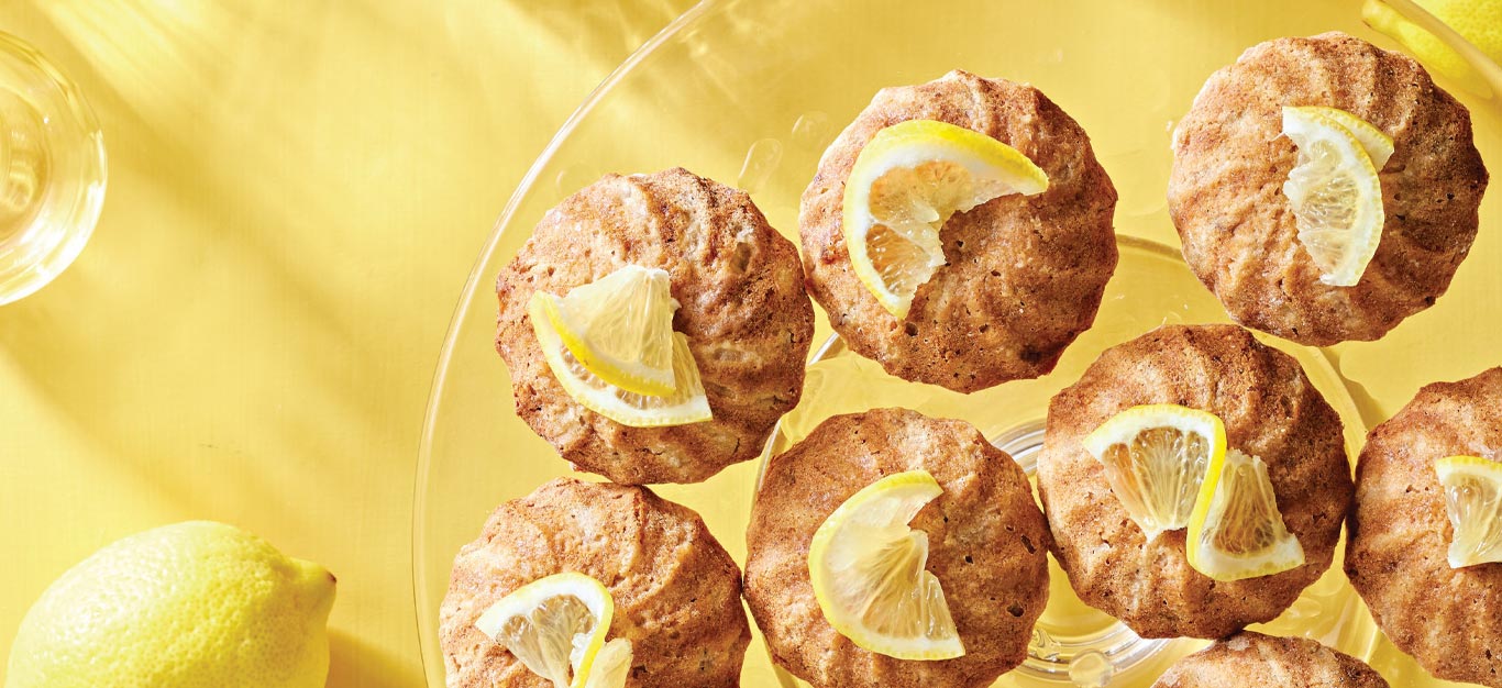 Lemon-Glazed Oatmeal Snack Cakes on a glass plate against a bright yellow background